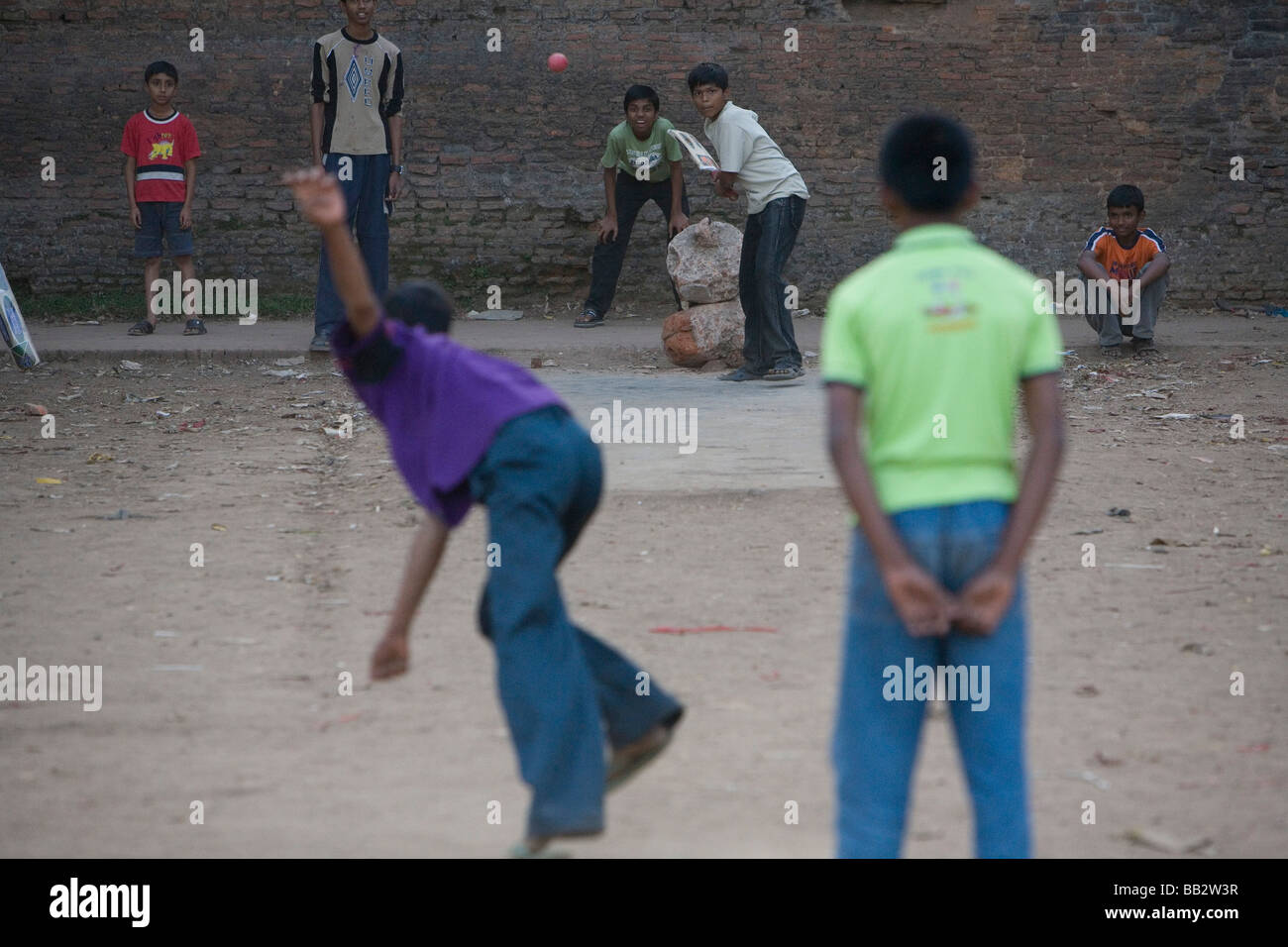 La vie quotidienne au Bangladesh ; les garçons à jouer au cricket sur un champ de terre. Banque D'Images