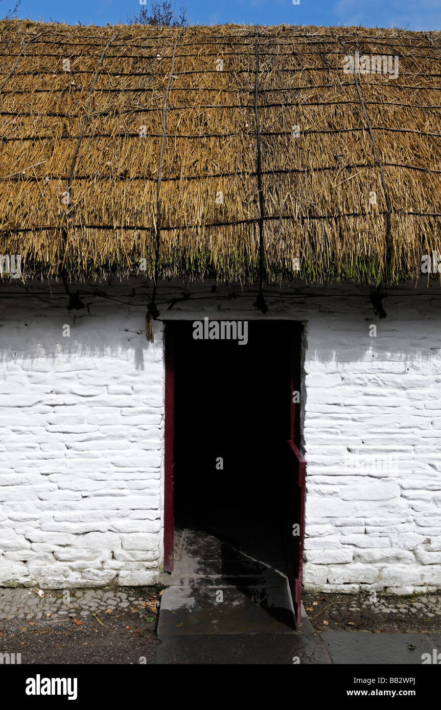 Cottage au toit de chaume avec porte en bois ouverte châssis de fenêtre blanc peint blanc maison traditionnelle en pierre bleu du ciel l'Irlande Banque D'Images