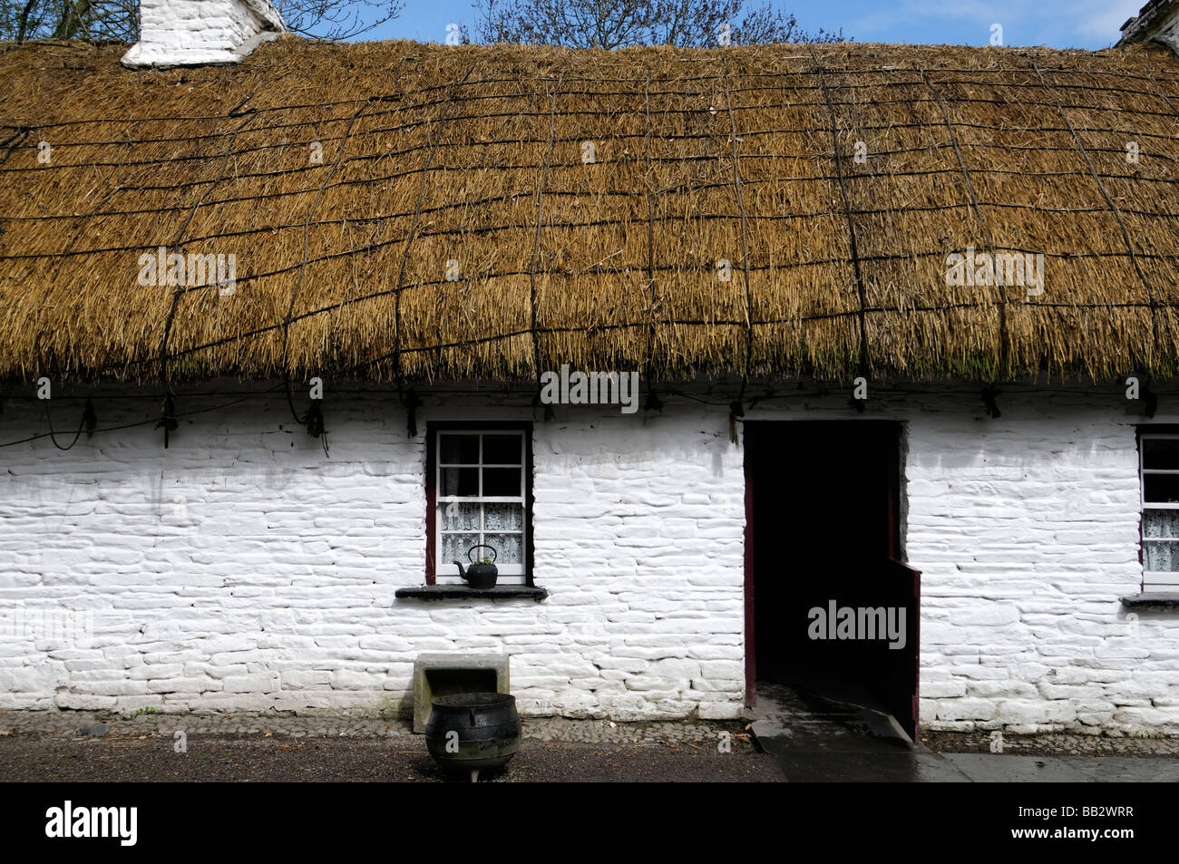 Cottage au toit de chaume avec porte en bois à moitié ouverte châssis de fenêtre blanc peint blanc maison en pierre traditionnelle de l'Irlande Banque D'Images