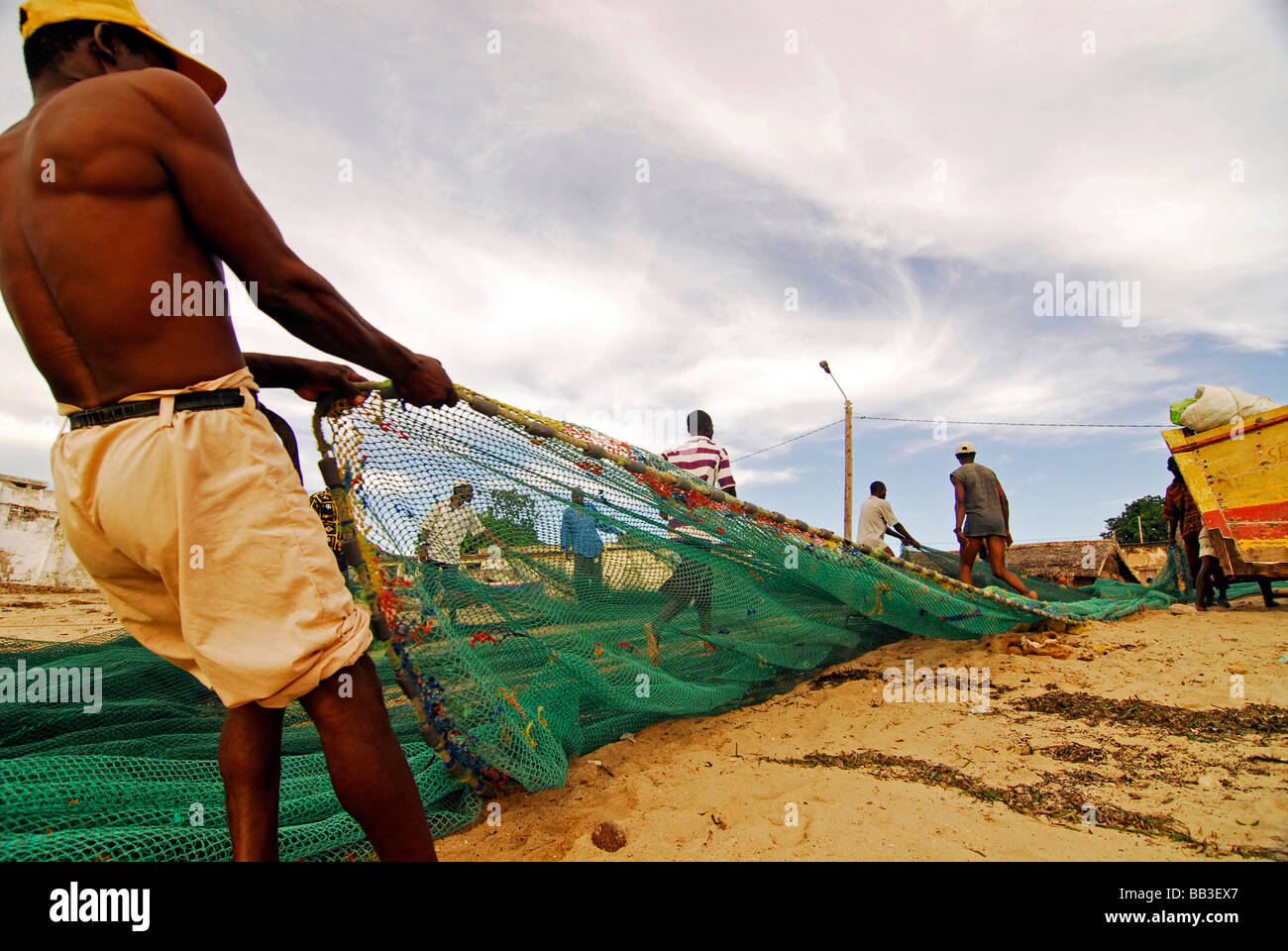 Le MOZAMBIQUE, l'Ilha de Mozambique. Groupe de pêcheurs solides barechest debout dans le sable, tirant un filet de pêche vert Banque D'Images