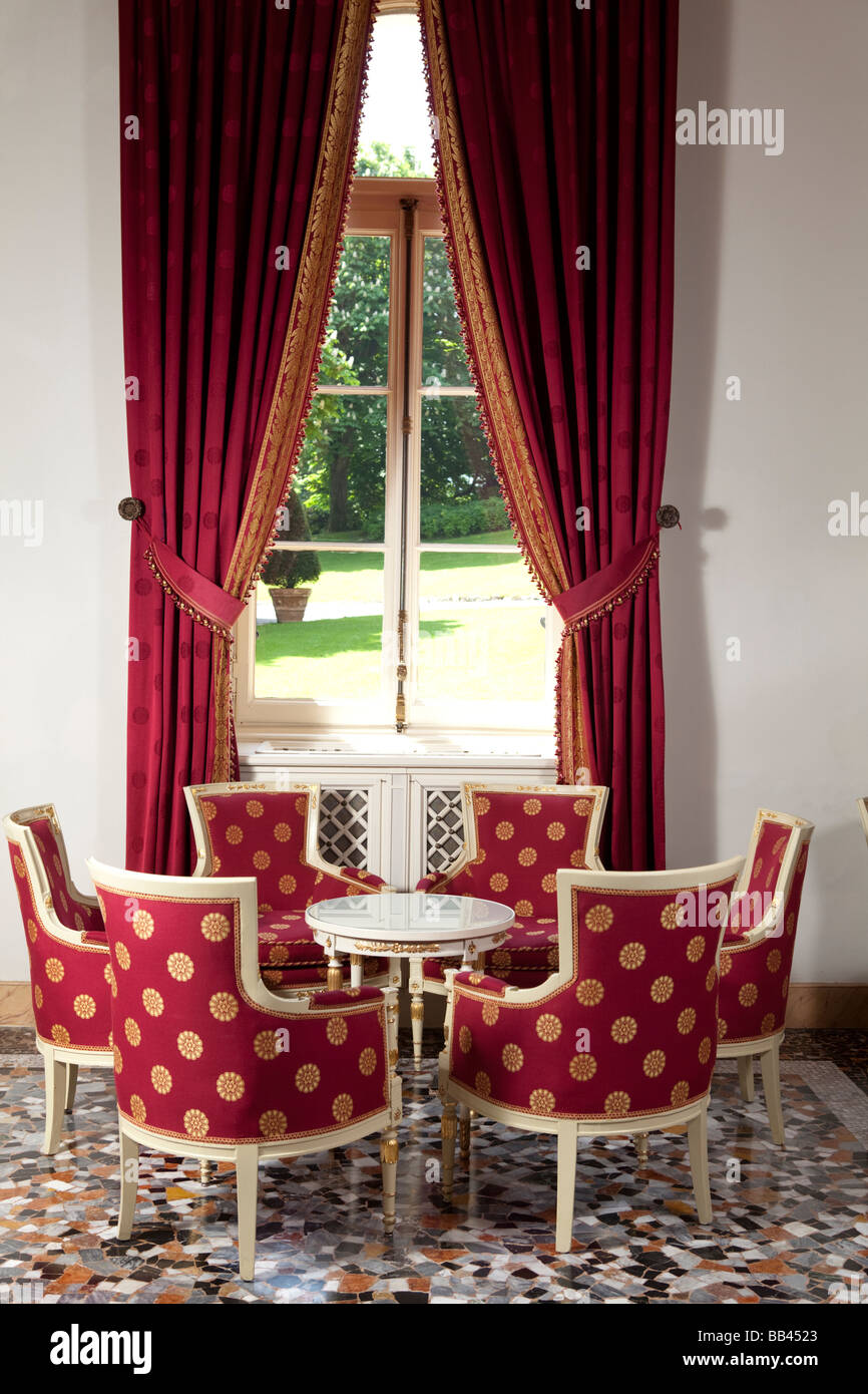 Table avec des fauteuils rouge par la fenêtre sur le jardin. Villa d'Este, Cernobbio, Côme, Italie Banque D'Images