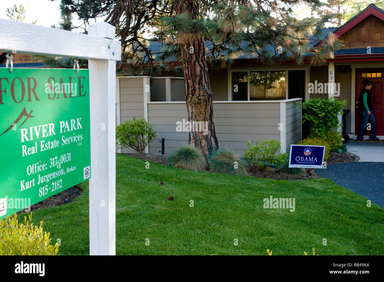 Un signe à vendre en face de la maison avec un poster d'Obama et une jeune femme sortant de la porte de Bend, Oregon. Banque D'Images