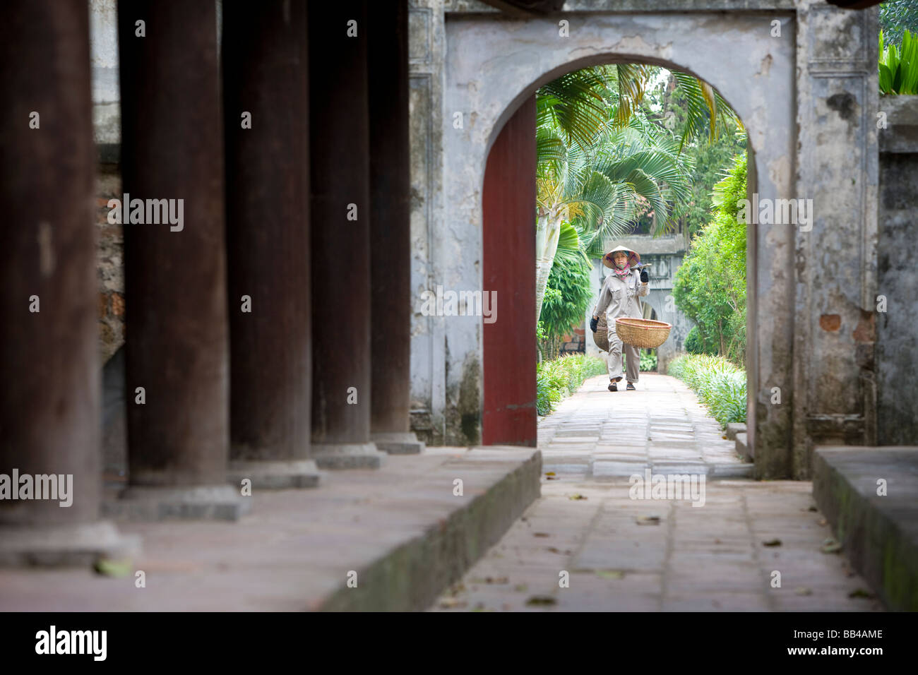 Un travailleur de terrain, marche le chemin à travers une porte à Quoc Tu Giam (National University) Banque D'Images