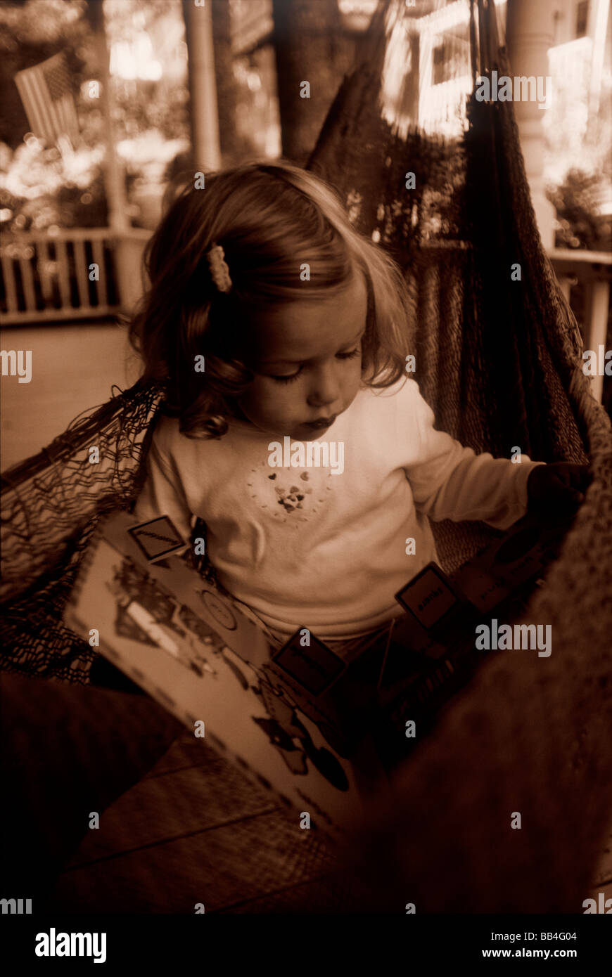 Une jeune fille lit un livre d'image à son chalet d'été dans la région de Bayside, Maine le Bay, Penobscott. Banque D'Images