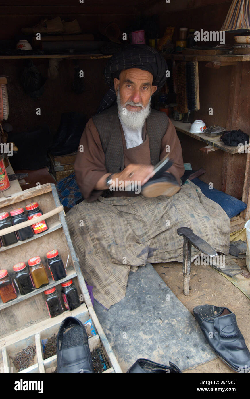 Un homme répare et fait briller les chaussures dans le bazar d'Turghondi,  une ville sur la frontière avec le Turkménistan Photo Stock - Alamy