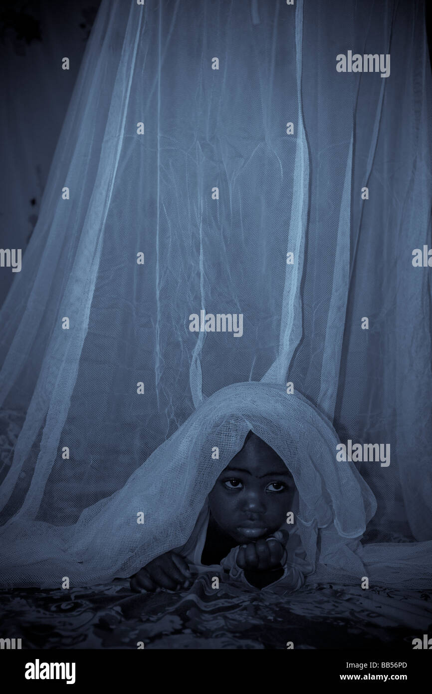 Un enfant dans la région de Garki Abuja, Nigéria peeks de sous un Permanet insecticide longue durée des moustiquaires traitées. Banque D'Images