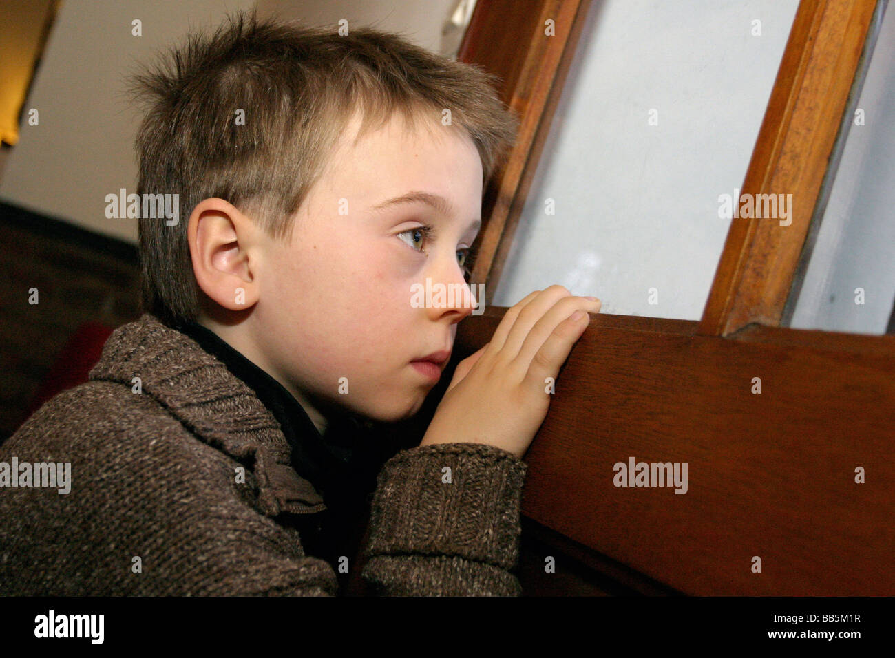 Triste et solitaire à l'enfant hors de la fenêtre de porte Banque D'Images