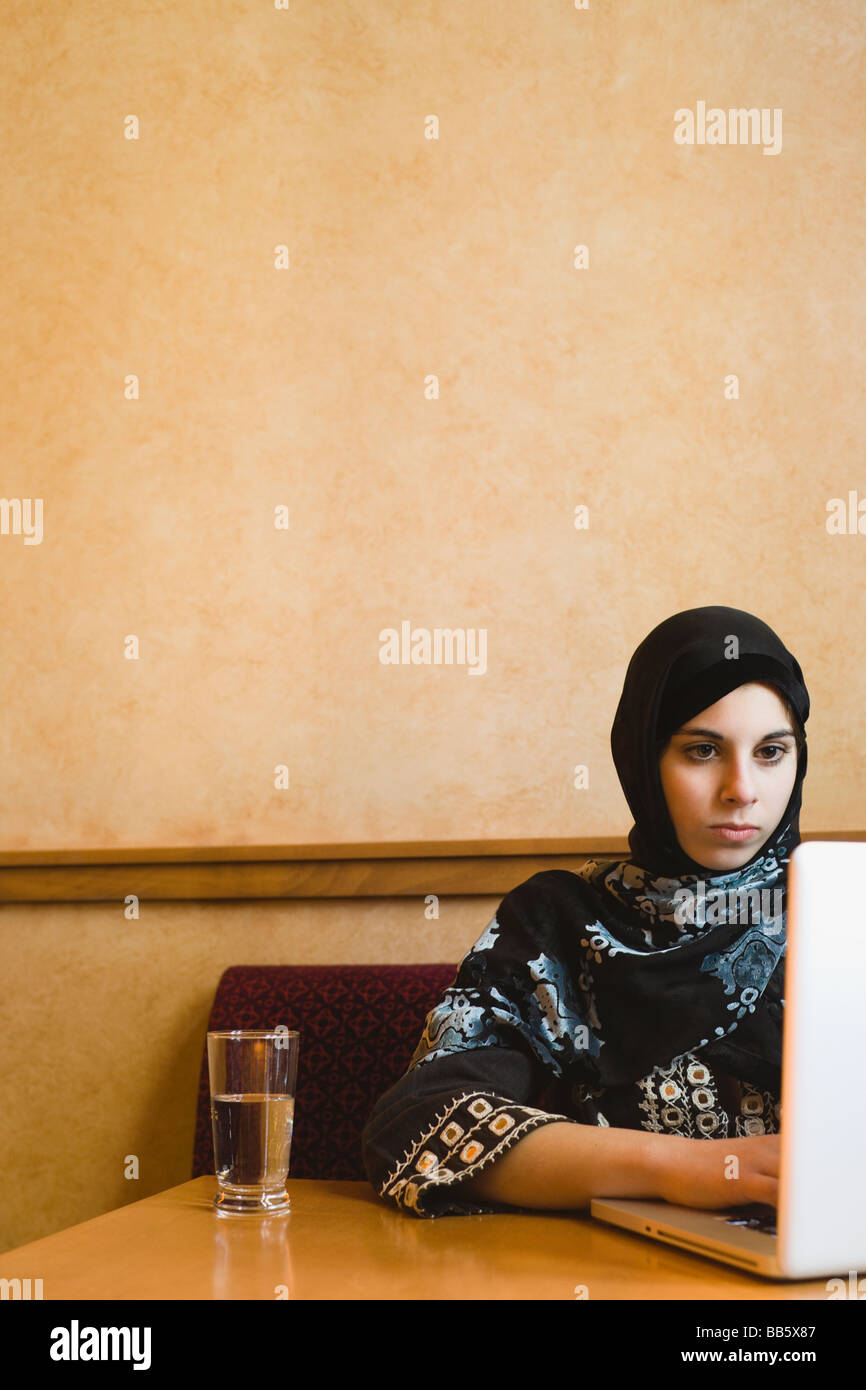 Adolescent moyen-orientale foulard en using laptop Banque D'Images