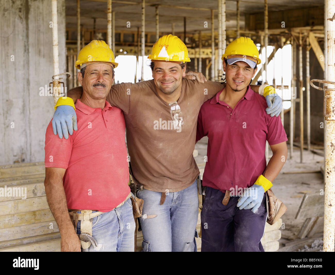 Les travailleurs hispaniques hugging on construction site Banque D'Images