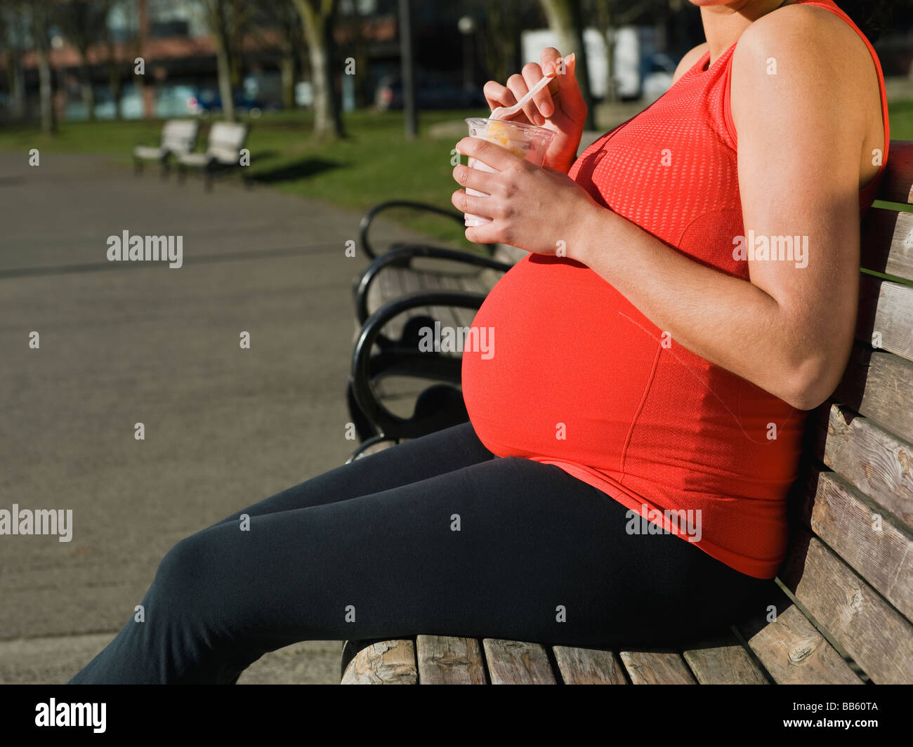 Pregnant Middle Eastern woman eating fruit in park Banque D'Images