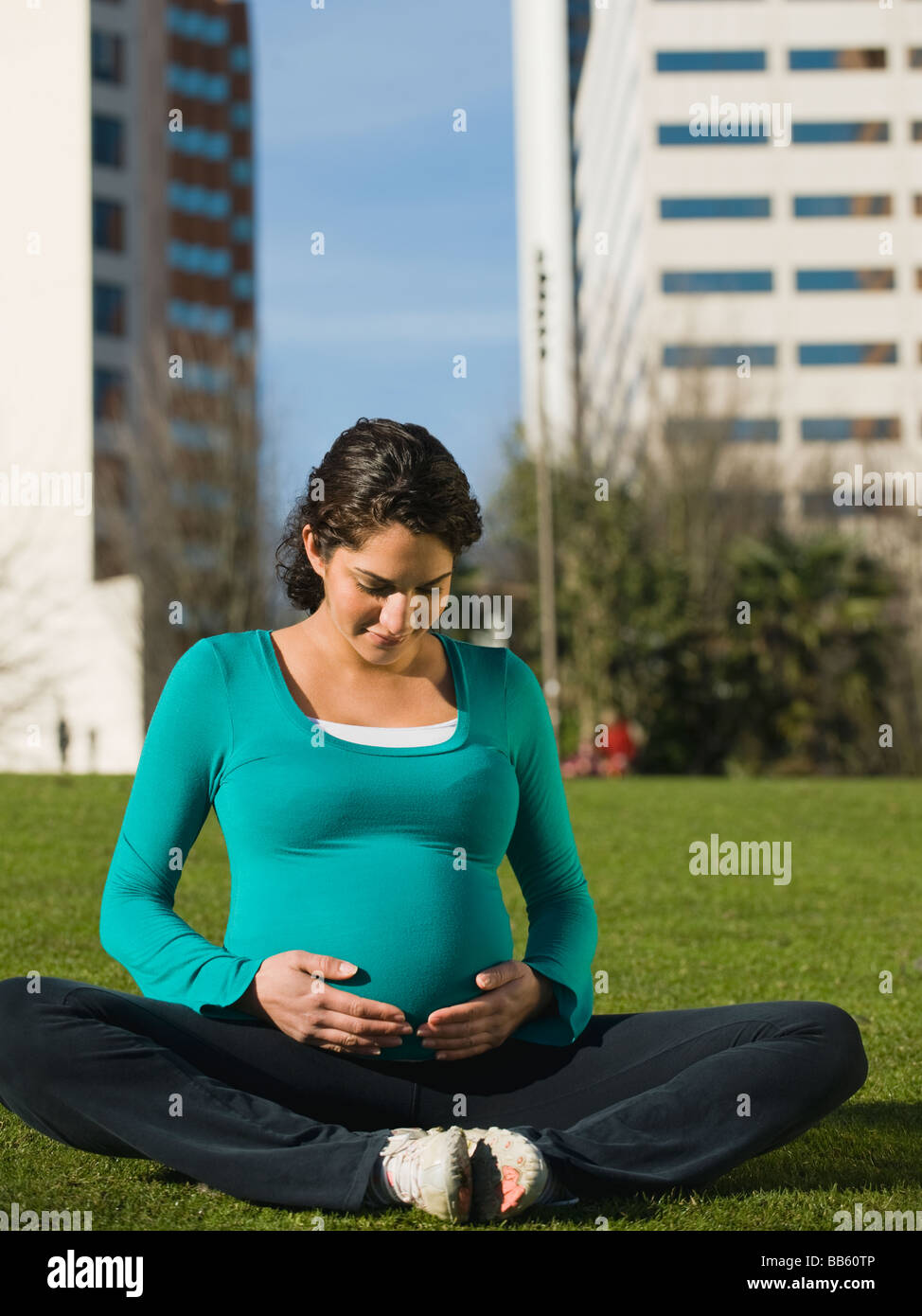Pregnant Middle Eastern woman practicing yoga in park Banque D'Images