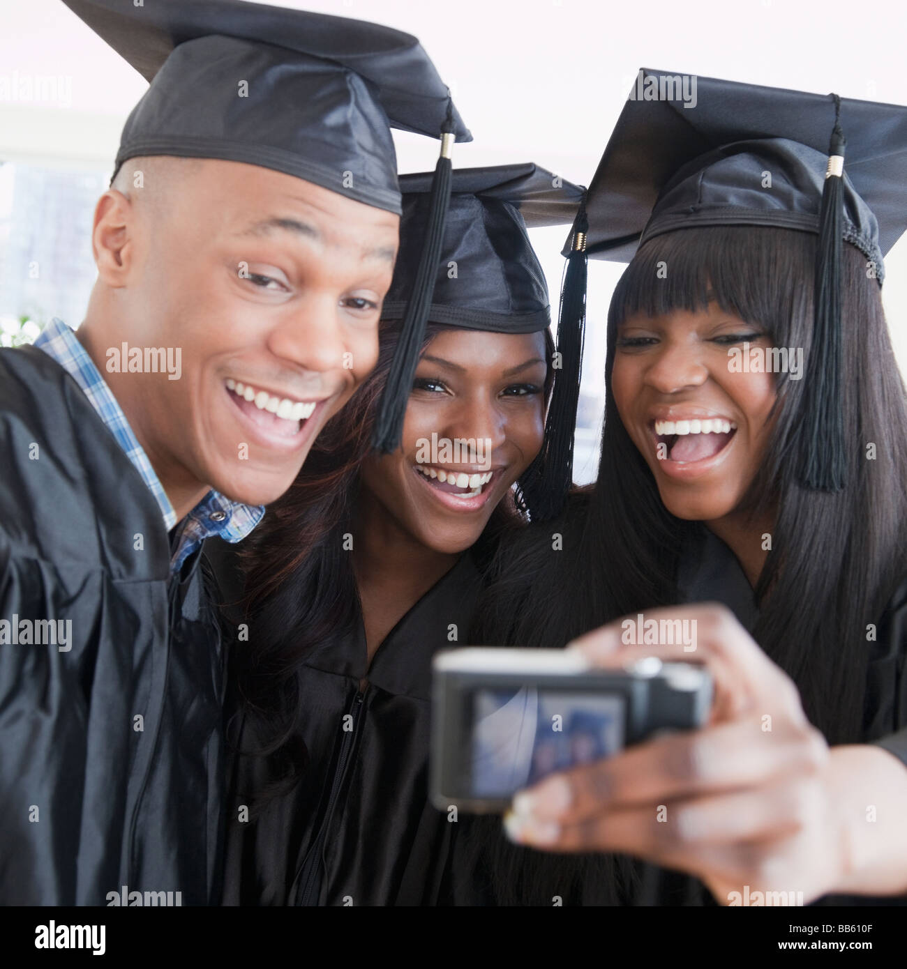 Amis africains en graduation cap and gown taking self-portrait Banque D'Images