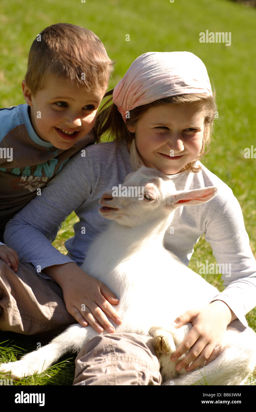 Boy and girl Lying in grass chèvre Banque D'Images