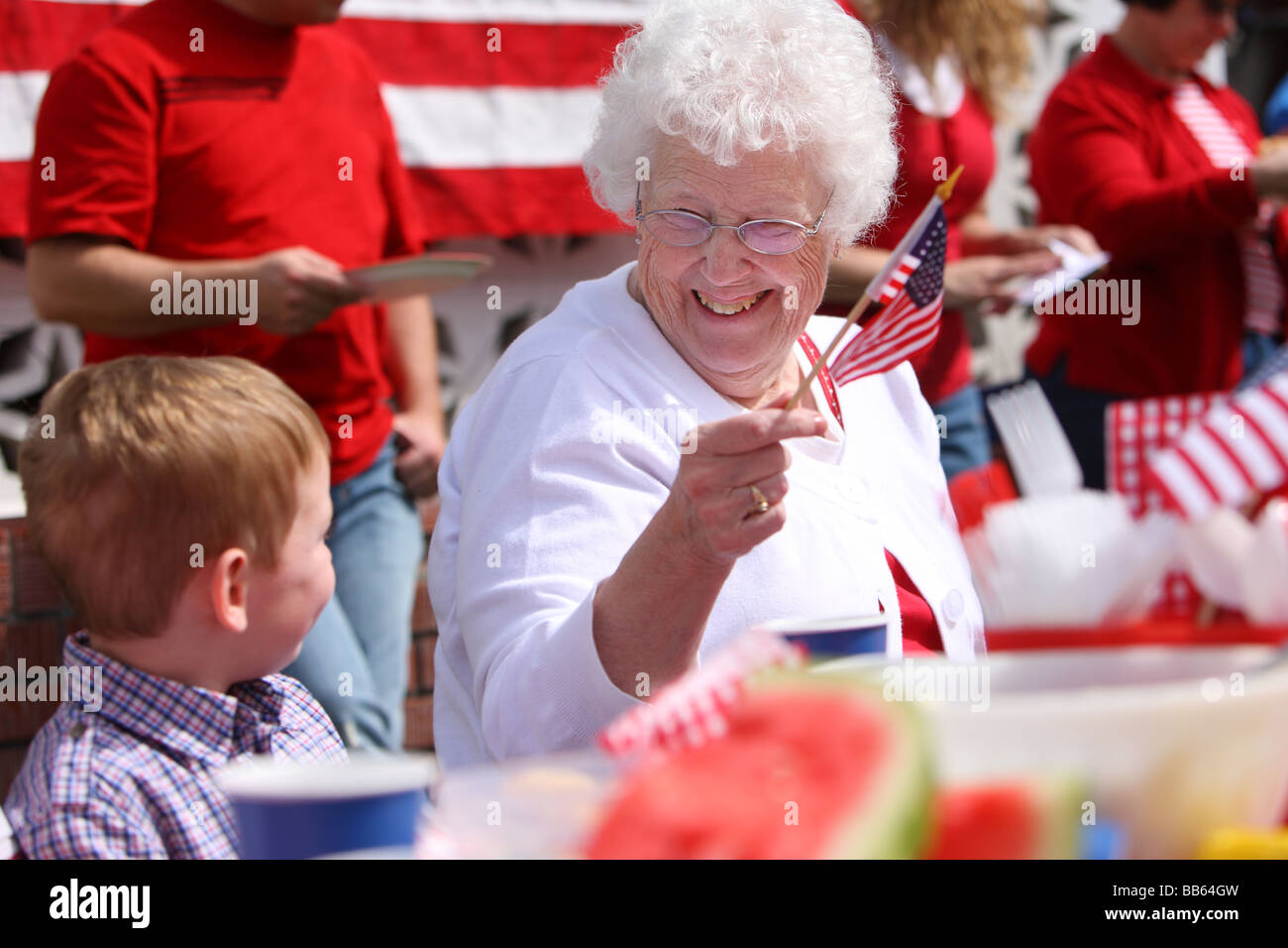 Femme âgée au barbecue familial waving American flag Banque D'Images