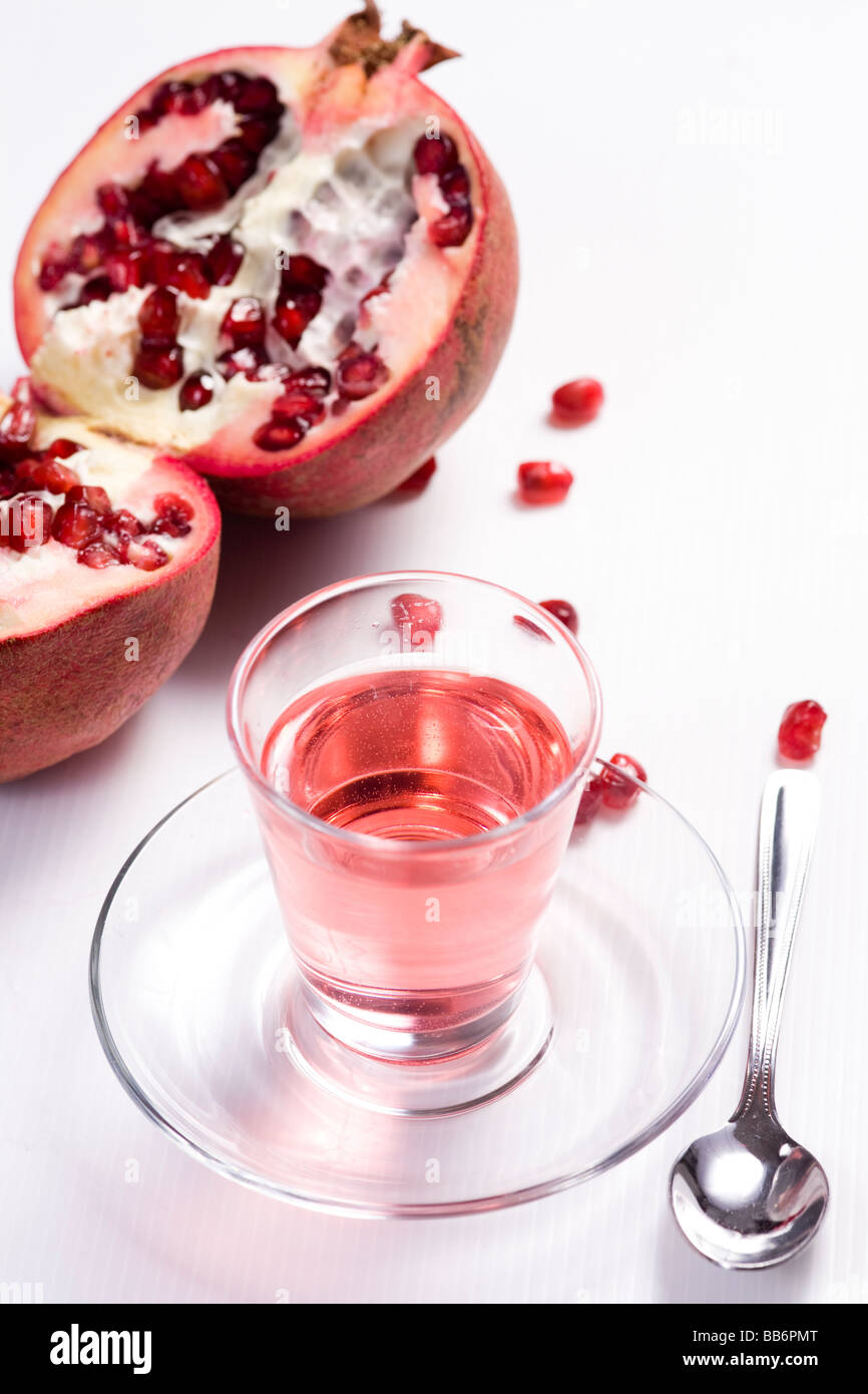 Pmegranate réduit de moitié sur fond blanc avec verre de jus de grenadine Banque D'Images