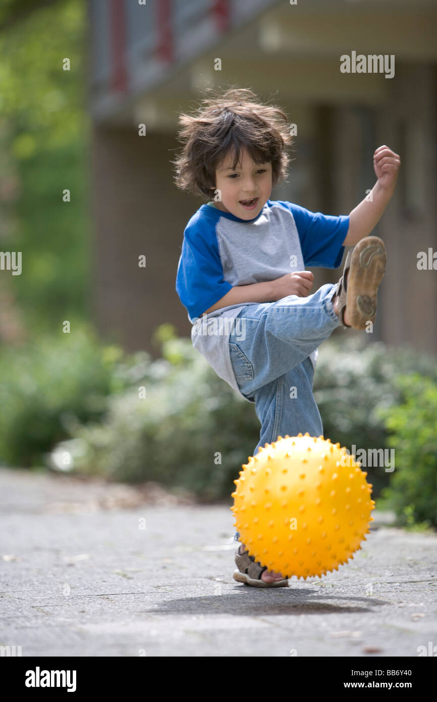 Petit Garçon jouant avec un ballon jaune Banque D'Images