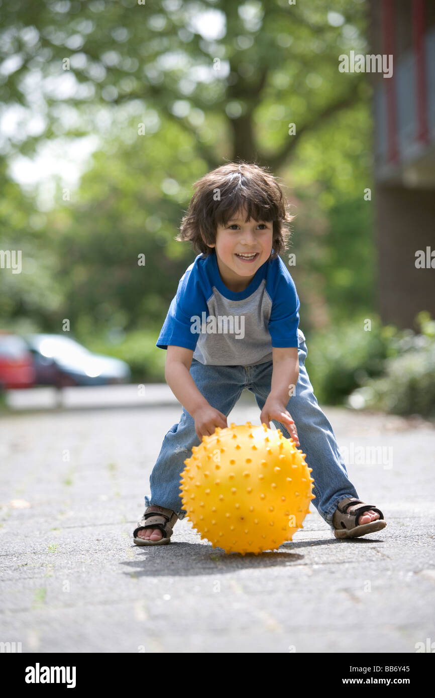 Petit Garçon jouant avec un ballon jaune Banque D'Images