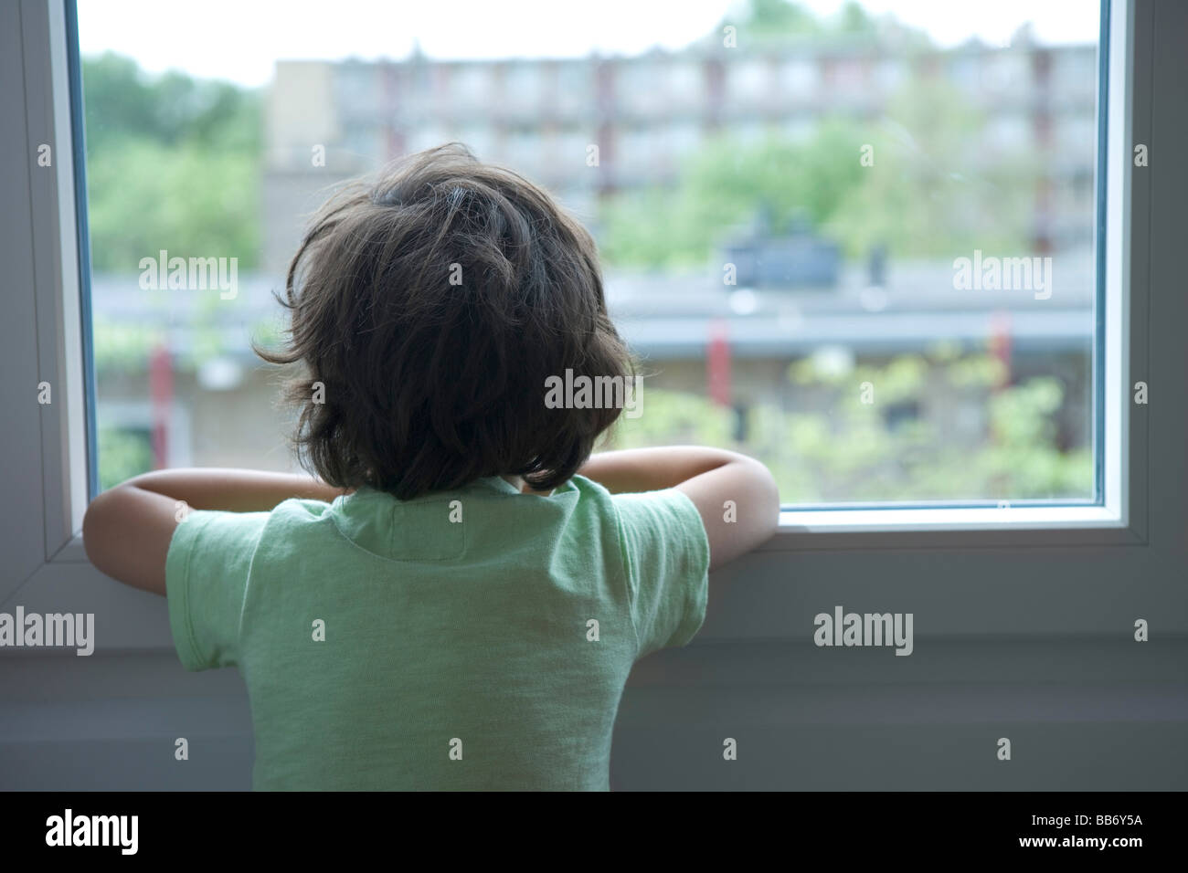 Petit garçon solitaire en regardant par la fenêtre Banque D'Images