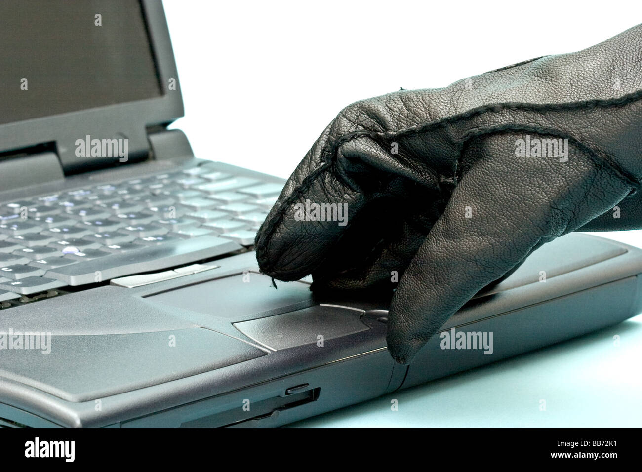 Une main gantée sur un clavier d'ordinateur portable Banque D'Images