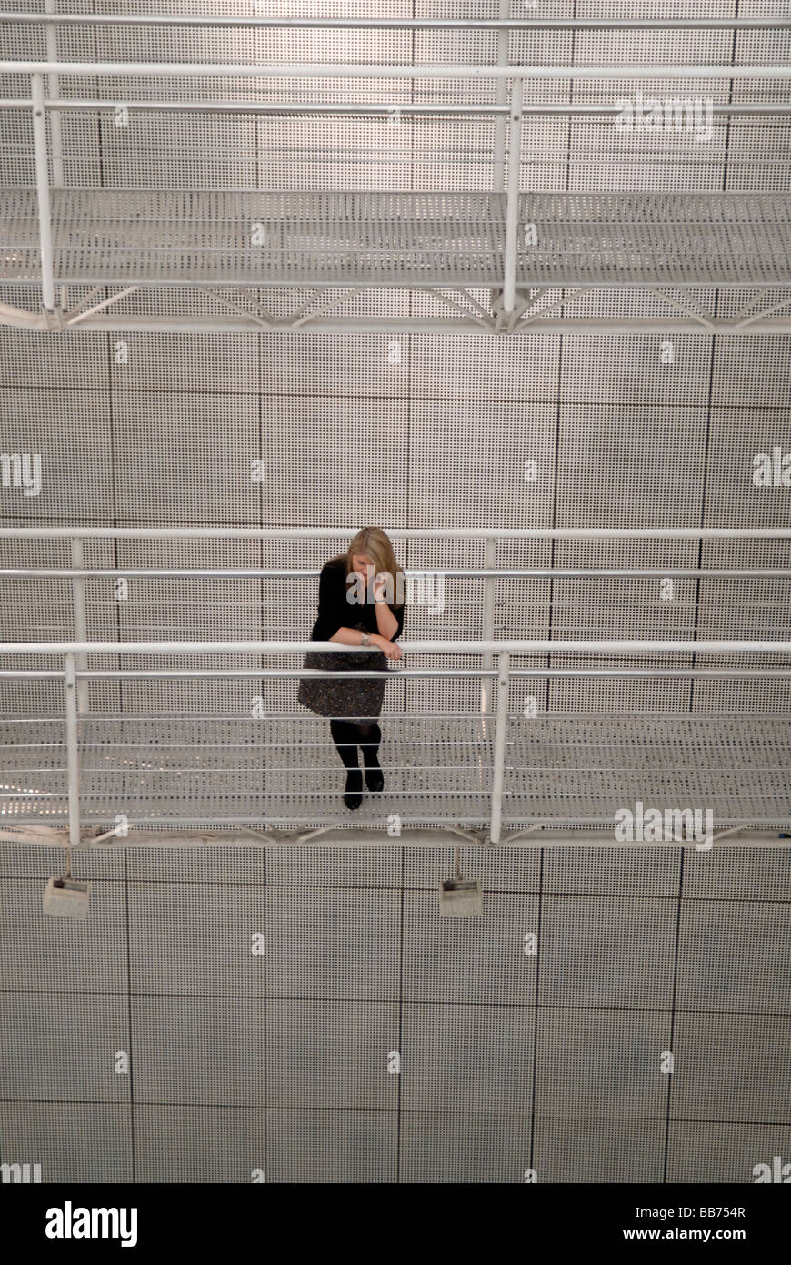 Femme debout sur la passerelle en acier entre les bâtiments de parler sur son téléphone portable, Londres, Angleterre Banque D'Images