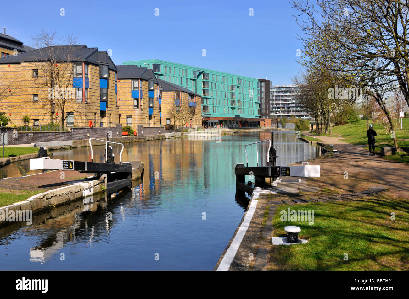 Réflexion hivernale dans Regents Canal à l'extrémité du mile pistes de halage avec Queen Mary University of London conception moderne de bâtiment bleu ciel ensoleillé Angleterre Royaume-Uni Banque D'Images