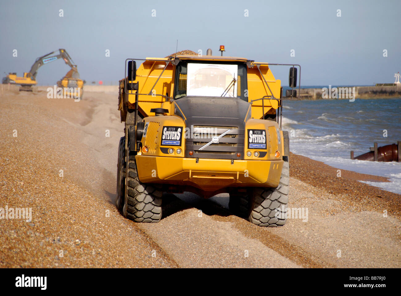 Big Yellow chariot en mouvement sur la plage de galets dans le cadre de la défense côtière, Hastings Sussex England Banque D'Images