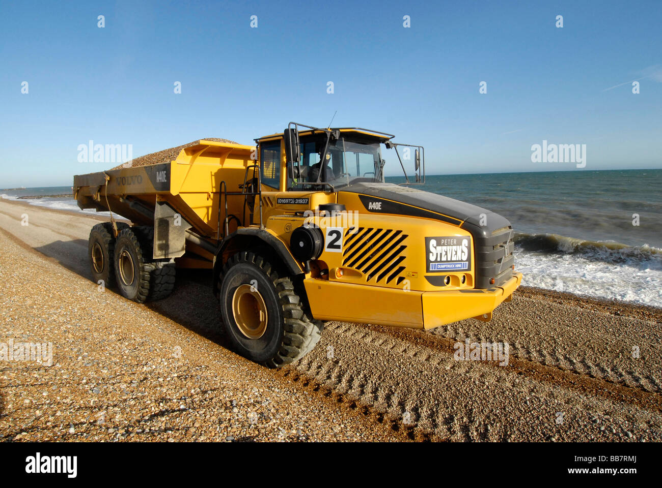 Big Yellow chariot en mouvement sur la plage de galets dans le cadre de la défense côtière, Hastings Sussex England Banque D'Images
