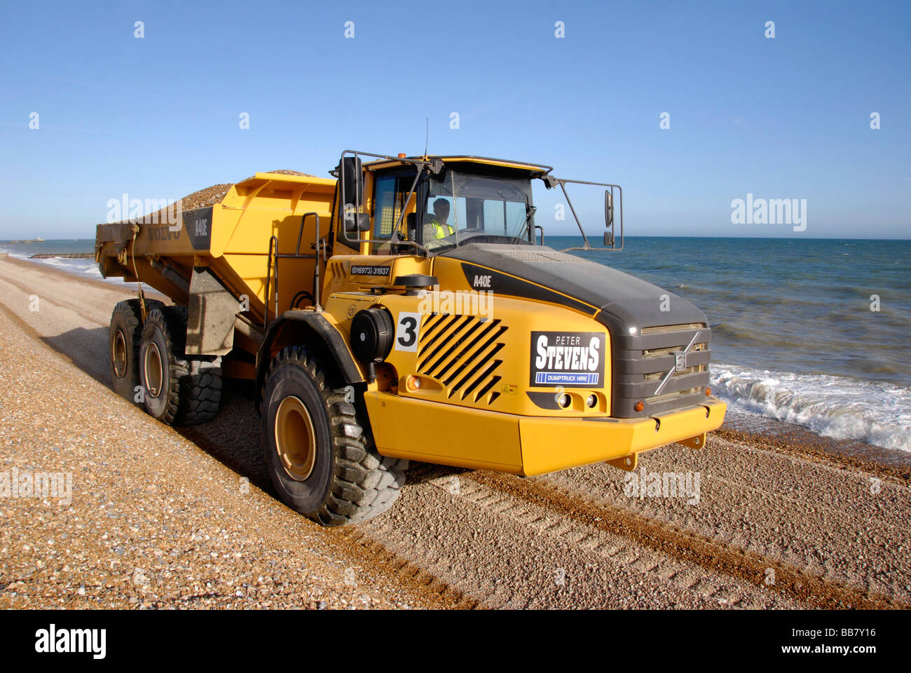 Big Yellow chariot en mouvement sur la plage de galets dans le cadre de la défense côtière, Hastings Sussex England Banque D'Images