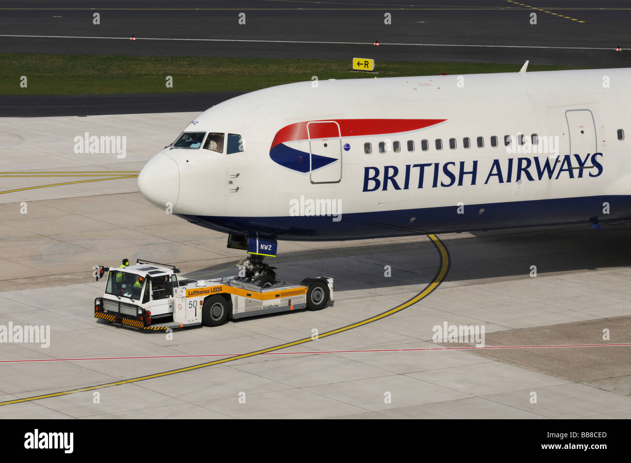 Gare de triage, véhicule avec l'avion de British Airways sur la piste, l'Aéroport International de Düsseldorf, North Rhine-Wes Banque D'Images
