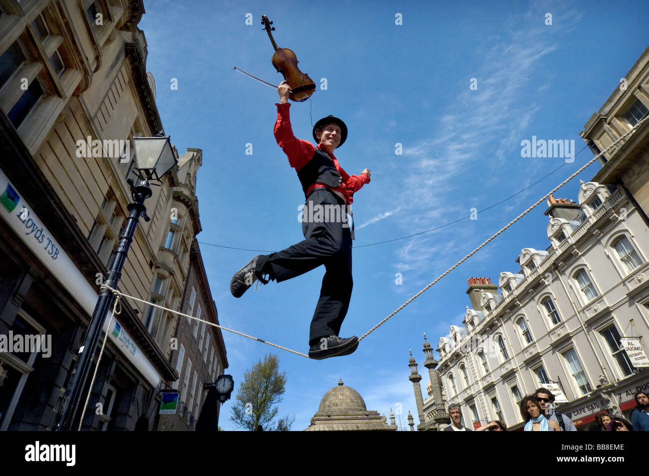 Théâtre de rue un musicien ambulant joue un violon tout en équilibre sur une corde raide au cours Brighton Festival Banque D'Images