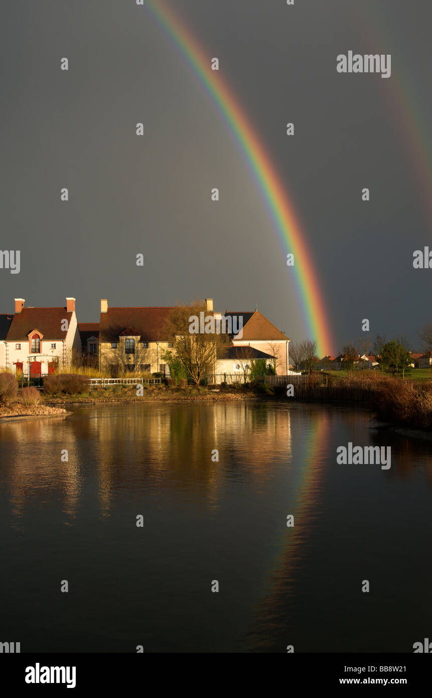 Ciel d'un noir avec double arc-en-ciel et reflétée dans le Nord de l'étang France Banque D'Images