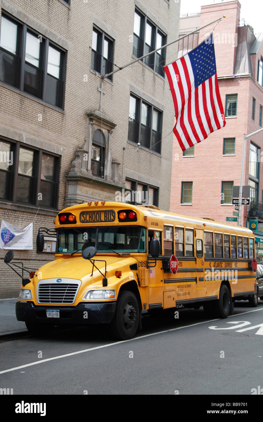 Un bus scolaire jaune américain traditionnel avec le Star Spangled Banner voler sur le bâtiment derrière. Banque D'Images