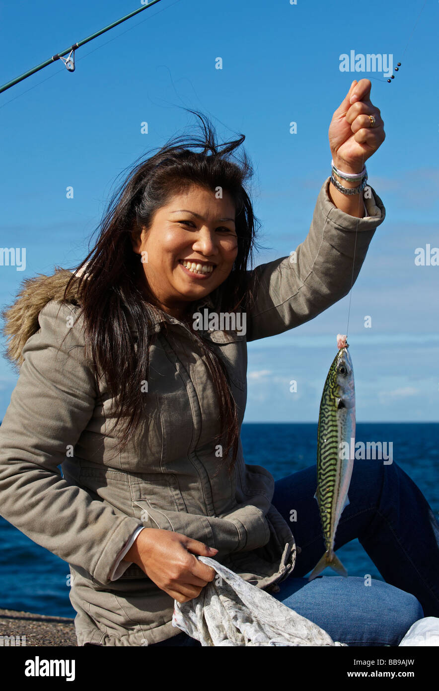 Une dame thaïlandaise avec un poisson au port de Peel à l'île de Man Banque D'Images