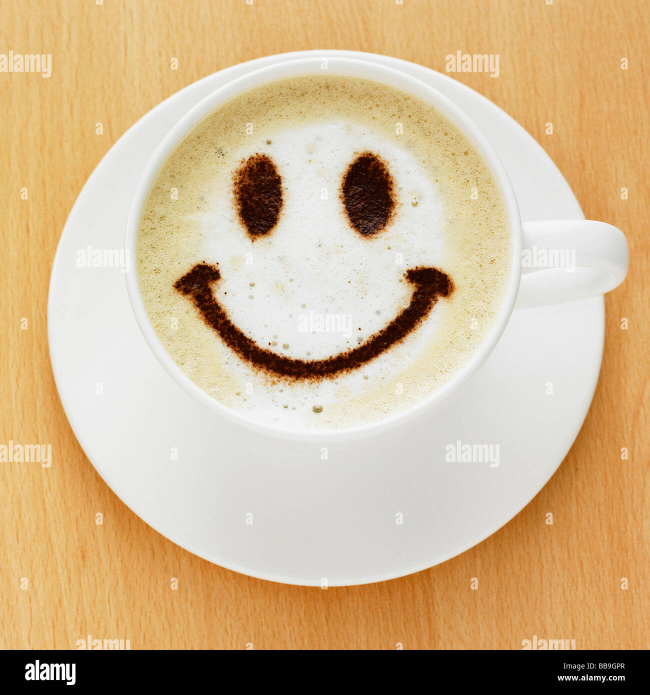 Une tasse de café cappuccino style avec un smiley sur le dessus dans le chocolat en poudre, tourné sur un dessus de table. Banque D'Images
