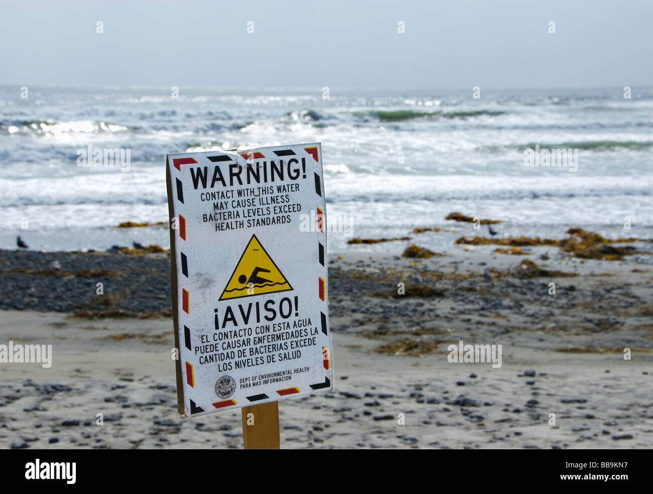 Inscrivez-vous sur beach avise les personnes de l'eau de mer contaminés possible. Signe est écrit en anglais et en espagnol. Banque D'Images