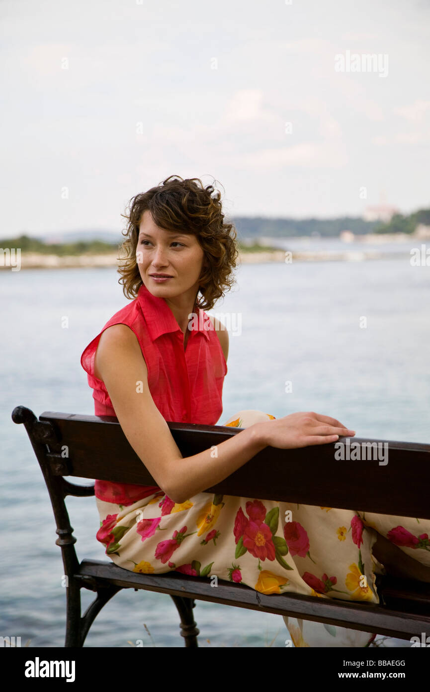 Une femme assise sur un banc au bord de la mer Banque D'Images