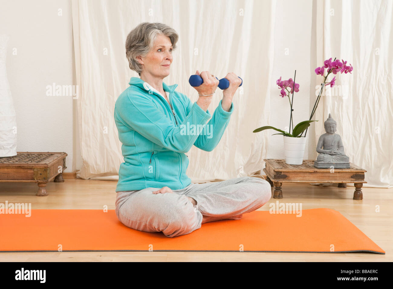 A senior woman working out avec des haltères dans un studio de yoga Banque D'Images