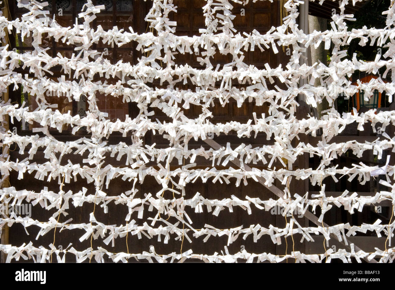 Gros plan de milliers de malchance O-mikuji, omikuji, livre blanc la fortune glisse lié à des stings parallèles formant un modèle au sanctuaire de Yasaka à Kyoto. Banque D'Images