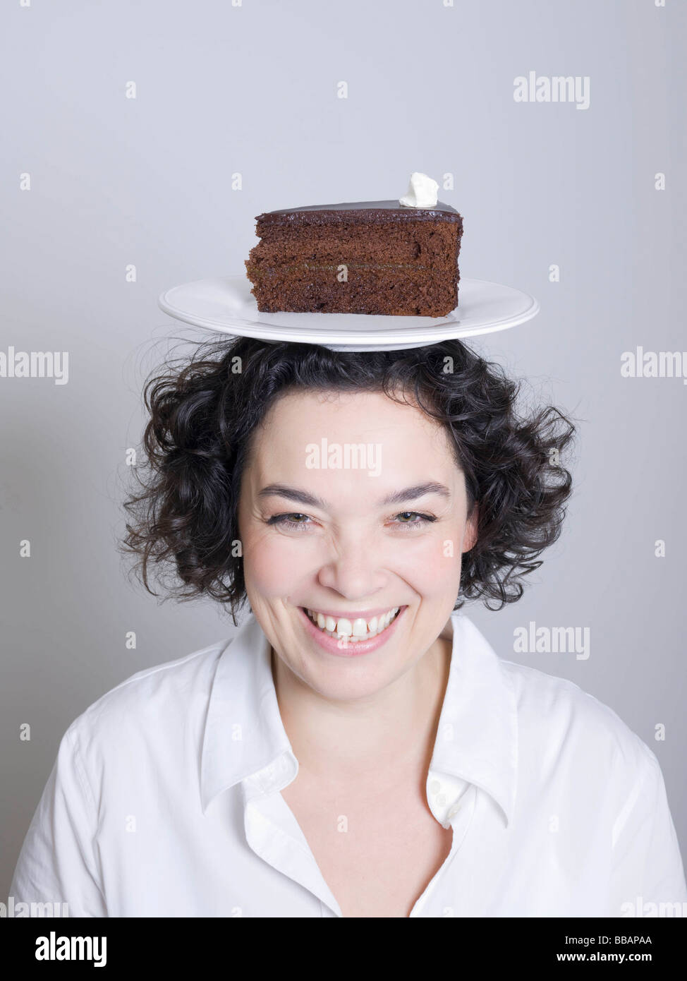 Femme avec une assiette de gâteau sur la tête. Banque D'Images