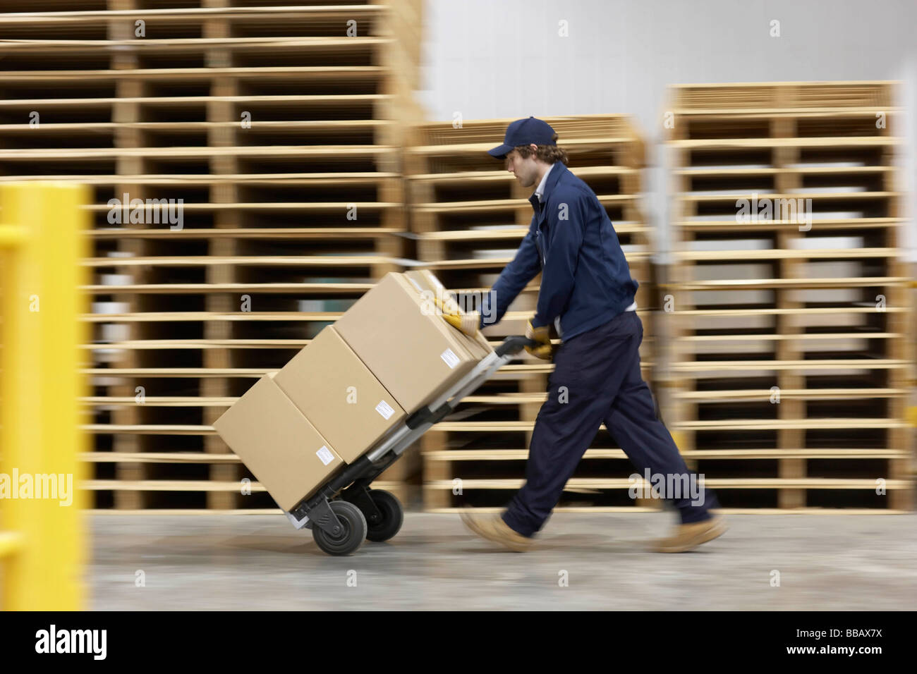 Poussant un chariot dans warehouse Worker Banque D'Images