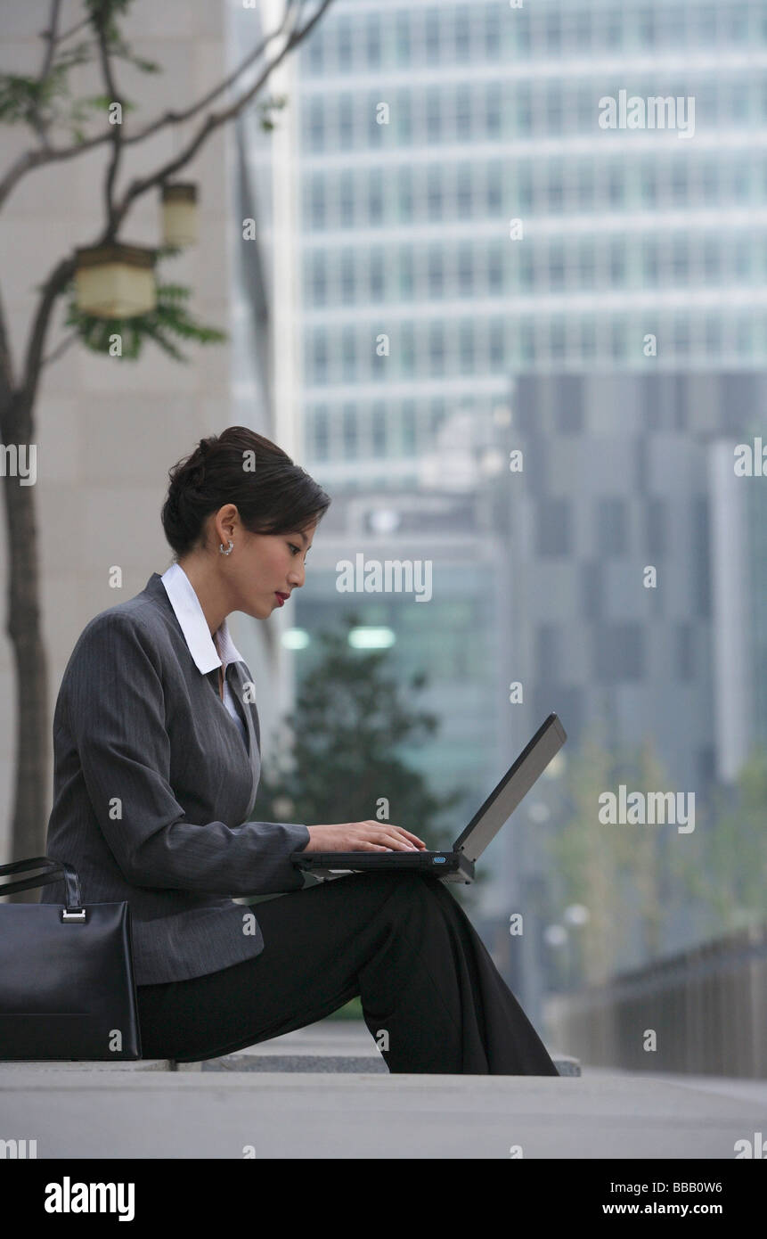 Une femme s'assied et utilise son ordinateur portable Banque D'Images