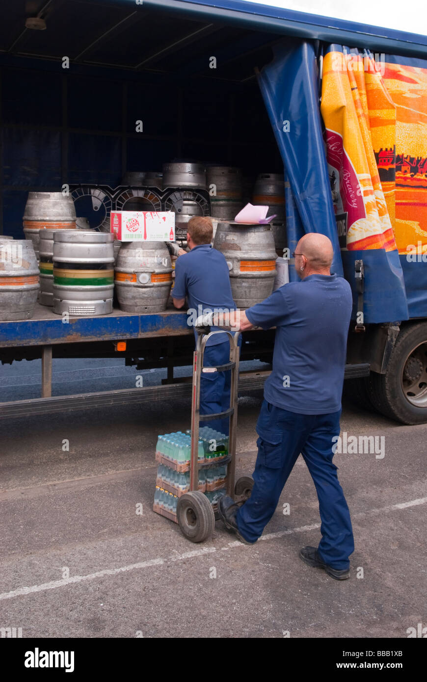 Deux membres du personnel de la brasserie Adnams le déchargement et la livraison ale et bière dans un pub de l'arrière d'un camion dans le Suffolk, Royaume-Uni Banque D'Images