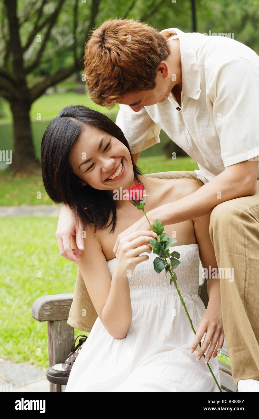 Couple on park bench, femme tenant une rose Banque D'Images