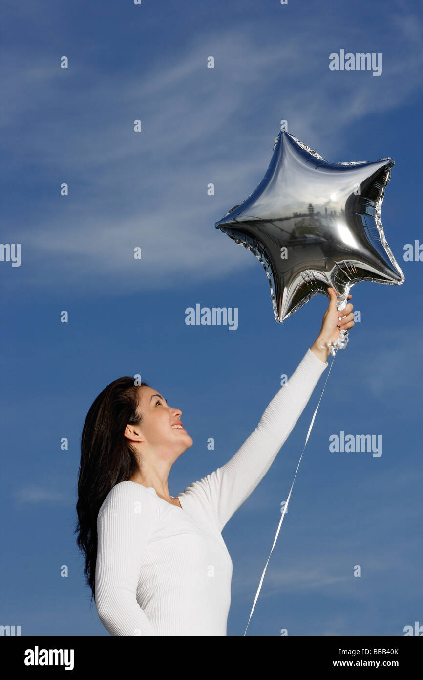 Jeune femme avec ballon en forme d'étoile d'argent Banque D'Images