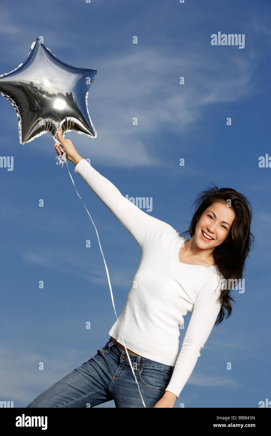 Jeune femme avec ballon en forme d'étoile d'argent Banque D'Images