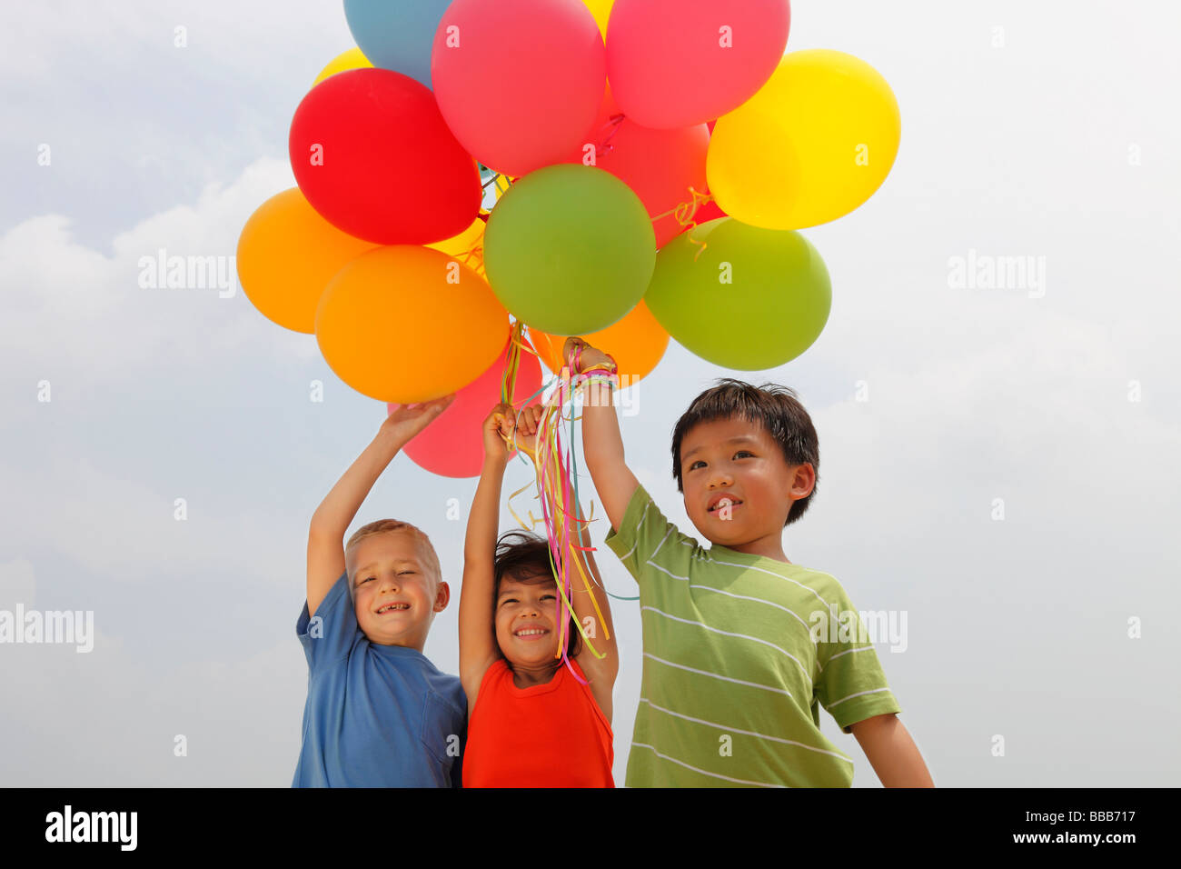 Trois enfants holding balloons. Banque D'Images