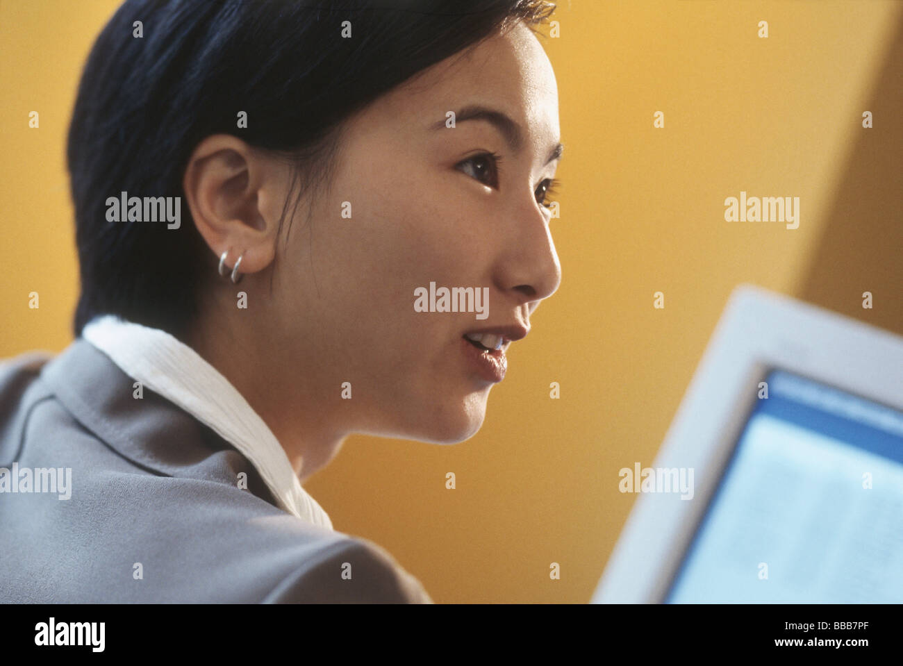 La femme en face de Moniteur d'ordinateur, profil, fond jaune Banque D'Images