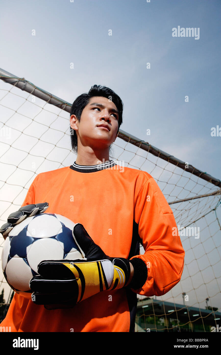 Gardien de but de soccer debout à côté de poteau de but, holding soccer ball Banque D'Images