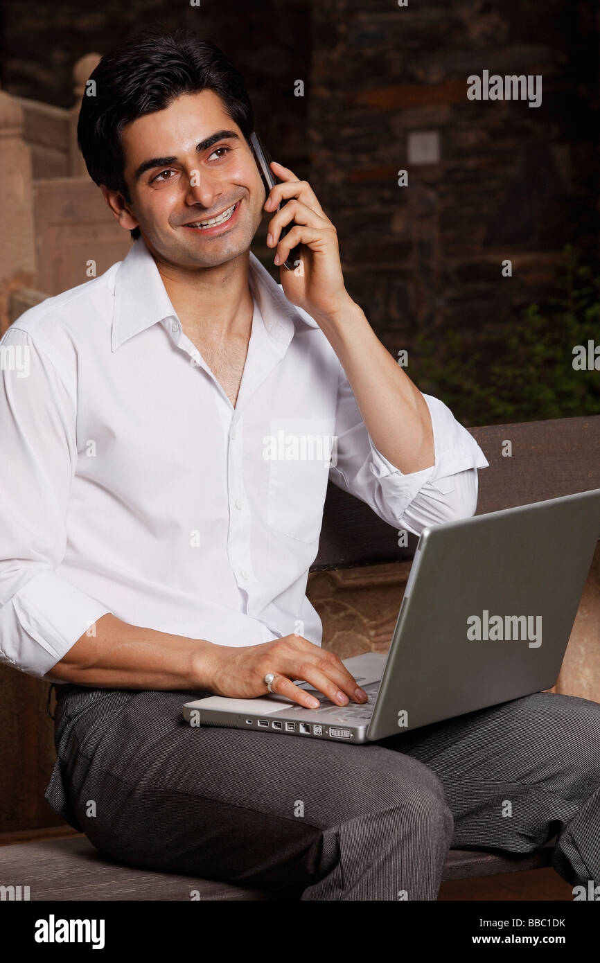 L'homme au téléphone, working on laptop computer Banque D'Images