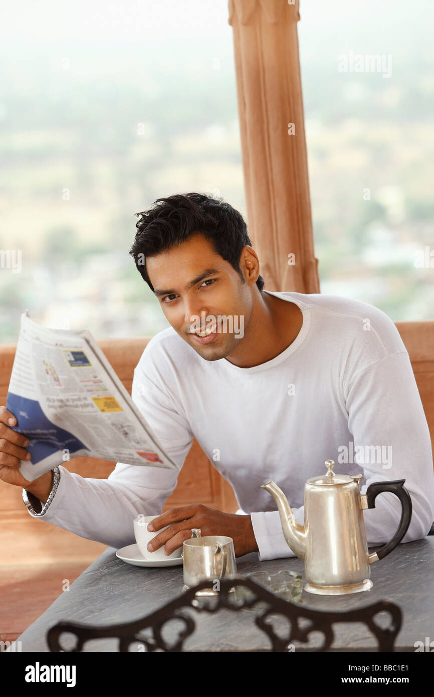 Homme lisant le journal du matin, boisson chaude Banque D'Images